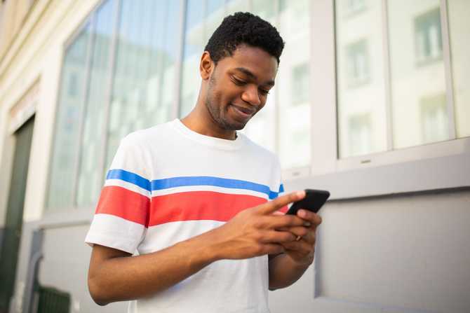 young-black-man-looking-at-mobile-phone-outside-2021-12-27-21-31-16-utc.jpg