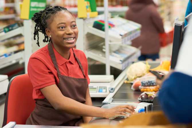 happy-young-cashier-in-workwear-looking-at-custome-2022-06-15-23-52-18-utc.jpg