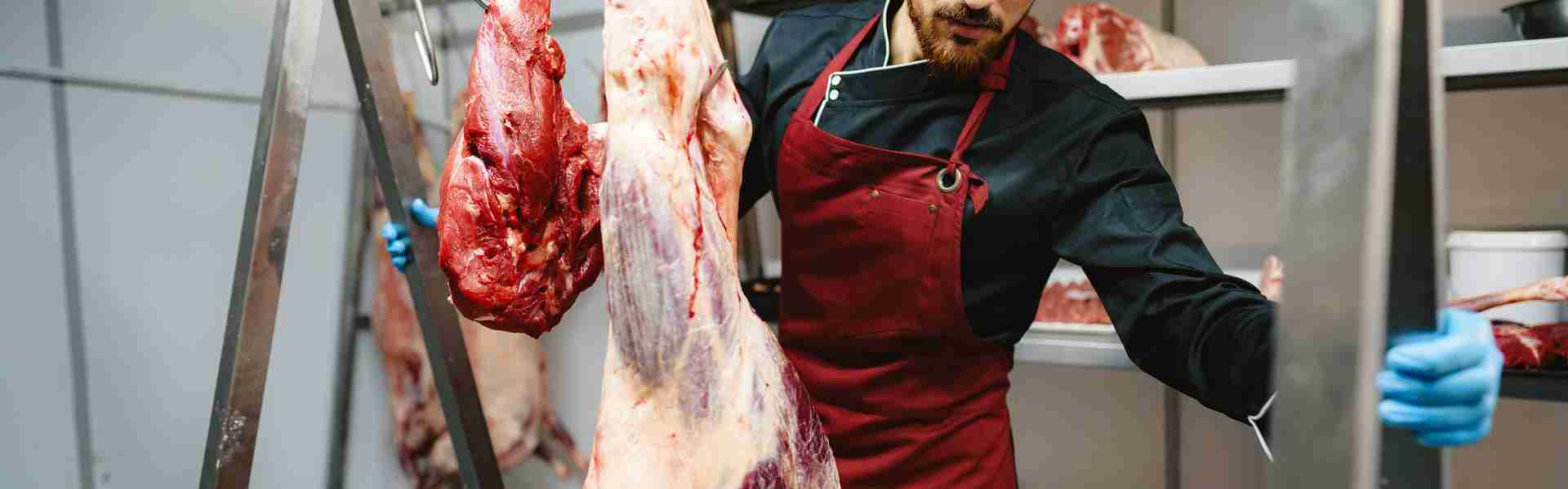 male-butcher-standing-by-meat-hanging-on-hook-in-m-2023-11-27-05-13-38-utc.jpg