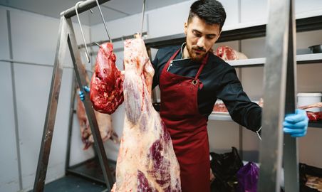 male-butcher-standing-by-meat-hanging-on-hook-in-m-2023-11-27-05-13-38-utc.jpg