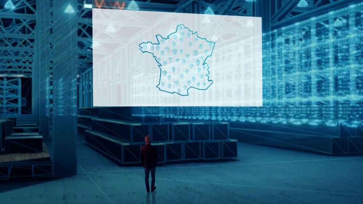 Homme regardant une carte de France sur un écran géant.