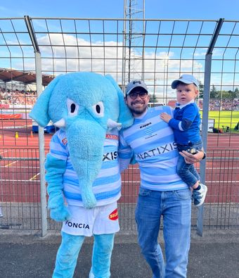 A fan and his child posing with the Racing 91 mascot.