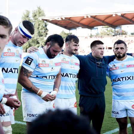 Racing 92 players in a circle, holding each other by the shoulders during a team reunion at a rugby match.