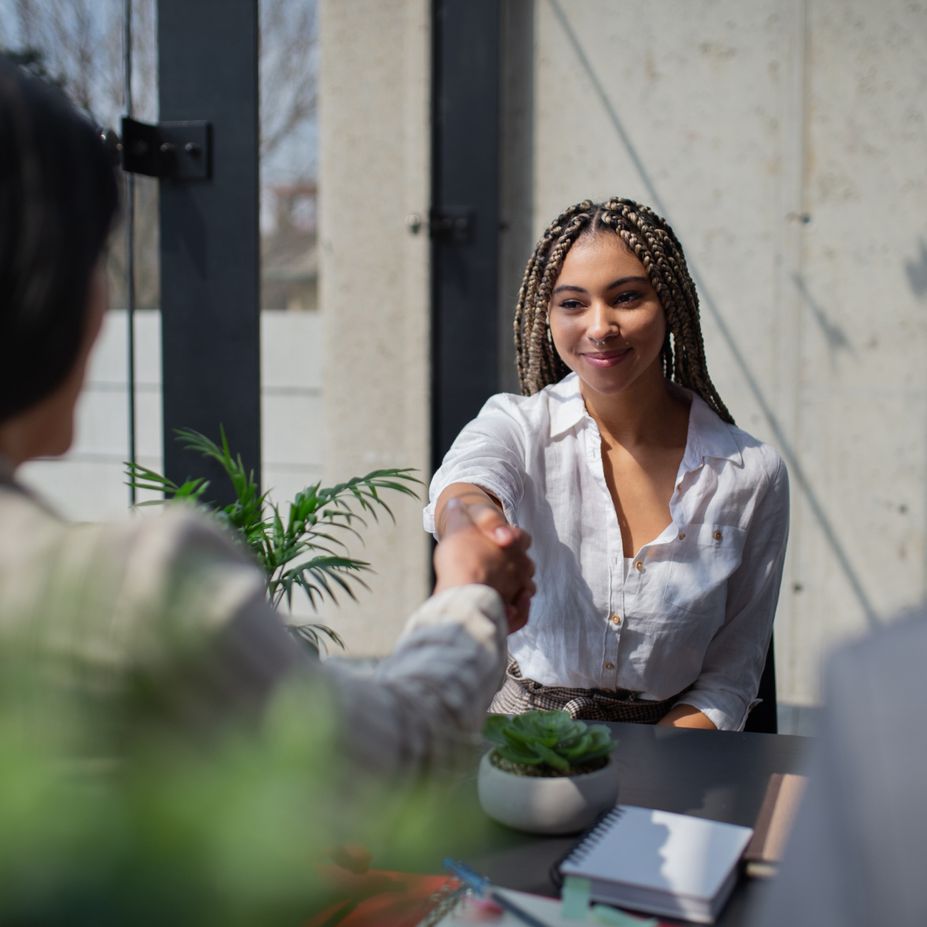 Une jeune femme serre la main d’une personne chargée de recrutement.